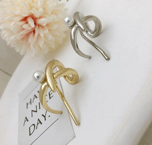 Detailed view of pearl hair clips in gold and silver finish with elegant twisted metal design