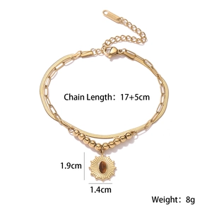 Macro detail of gold layered bracelet with sunburst pendant and brown cat eye stone