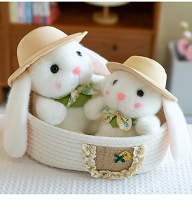 Close-up of two cute plush rabbits with straw hats and bows in a woven basket