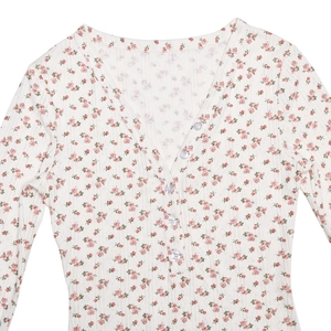 Détail de la barboteuse fleurie blanche avec col en V, fleurs rouges et boutons