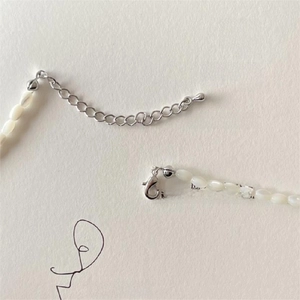 Detailed view of silver lobster clasp and adjustable extension chain on shell bead necklace