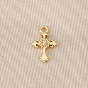 Detailed close-up of 18K gold plated cross pendant with cubic zirconia inlay on fabric
