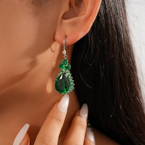 Close-up of model wearing elegant silver earrings with green water drop zircon gemstones