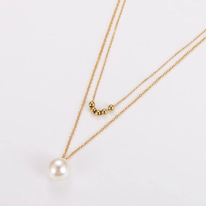Détail d'un collier double rang en or avec petites billes et un grand pendentif en perle