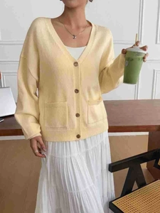 Detail of yellow knit cardigan with V-neckline, buttons and pockets for casual autumn wear