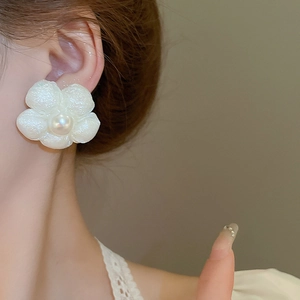 Elegant white fabric flower earrings with center pearl on model for a chic look