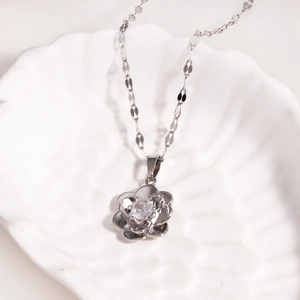Detail of silver rose flower pendant necklace with clear zircon stone in shell plate