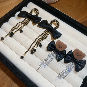 Detailed view of bear and bow earrings with rhinestones and fringes in a jewelry box