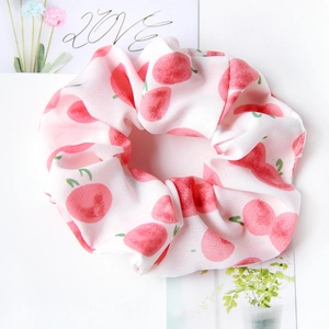 Detail of white scrunchie with pink apple pattern made of soft chiffon fabric