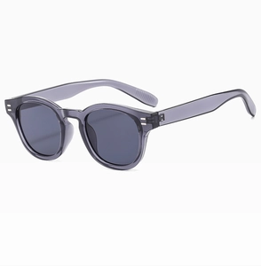 Close-up of translucent grey oval sunglasses featuring vintage double metal stud details