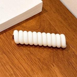 Détail d'un élastique spirale blanc avec clip en métal doré sur une table en bois
