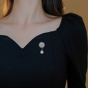 Macro detail of gold plated flower brooch with sparkling marquise zircons and white pearl