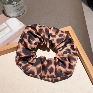Detail of leopard print fabric scrunchie displayed on a rustic wooden tray with props
