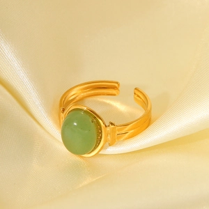 Detail of vintage 18K gold plated ring with large oval green gemstone on silk