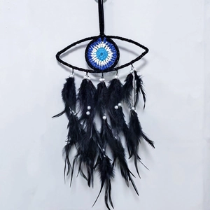 Detail of handmade evil eye dreamcatcher with black feathers and woven blue core