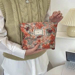 Floral corduroy makeup bag held by hand, vintage orange and olive pattern detail