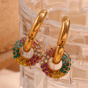 Close-up of gold hoop earrings with colorful rainbow cubic zirconia charms on textured glass
