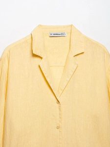 Close-up detail of yellow linen shirt collar and buttons with natural fabric texture