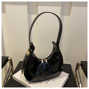 Detail of glossy black patent leather crescent underarm bag with gold metal zipper closure