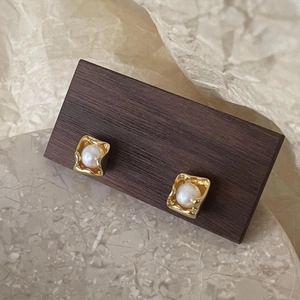 Detailed view of square baroque pearl stud earrings in gold irregular metal frames