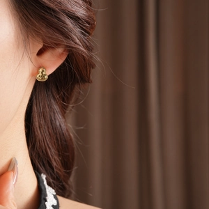 Close-up of 18k gold plated gourd earrings worn by a model with elegant glossy finish