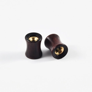 Detail of hollow sandalwood and gold stainless steel ear gauges with flared design