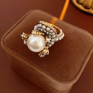 Detailed close-up of a vintage golden pearl flower ring on a brown velvet jewelry box