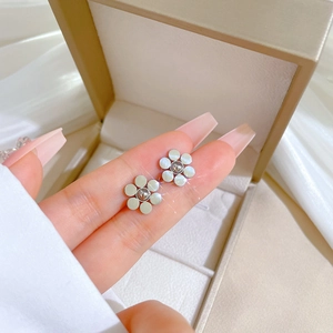 Macro detail of six-petal flower stud earring with mother-of-pearl finish and silver tone
