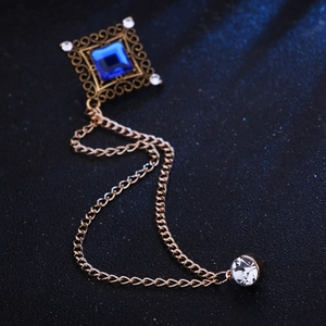 Detail of vintage square brooch with blue gemstone, tassels, and golden metal chain