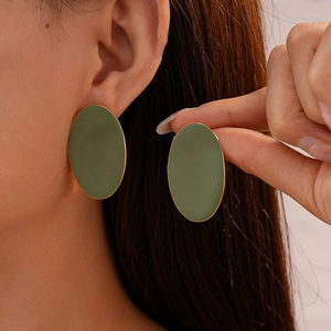 Minimalist matte olive green oval stud earrings shown on ear for size perspective