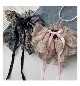 Detailed view of floral chiffon bow hair clips with long ribbons on a white surface