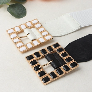 Flat lay of black and white elastic waist belts with golden square acrylic buckles