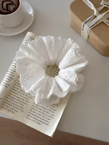 Macro detail of white floral lace scrunchie with intricate embroidery on vintage paper