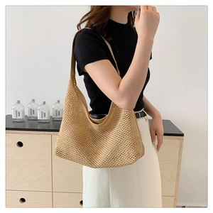 Detail of woven straw tote bag showing texture and drape on model in a minimalist setting