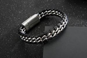 Detailed close-up of woven black leather and silver metal chain bracelet with polished clasp