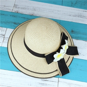 Détail d'un chapeau de paille tissé à la main avec ruban noir et touches de fleurs blanches