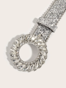 Close-up of a silver belt featuring a sparkling rhinestone round buckle and sequined band