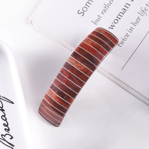 Detail of elegant red-brown wood grain and white striped spring hair clip on book