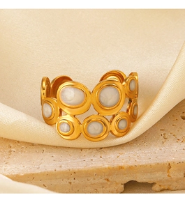 Macro shot of gold plated geometric ring with white enamel inlay on satin and stone
