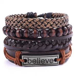 Gros plan de bracelets en cuir superposés avec cordons tressés et une plaque gravée Believe