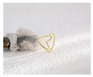 Detail shot of a minimalist gold hollow heart ring on a natural stone surface