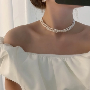 Detailed view of elegant triple-strand freshwater pearl choker on a female model