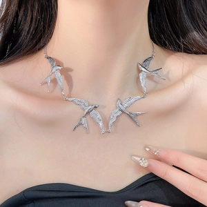Silberne Halskette mit Schwalbenanhängern und Vogelflügeln am Hals eines Models