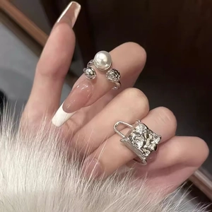 Silver rings featuring a large pearl flower and creative handbag design on a model's hand