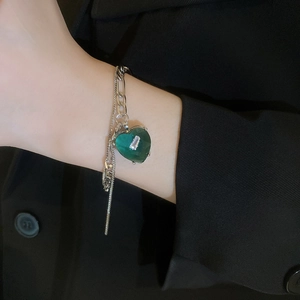 Detail view of double-layered silver bracelet featuring a green heart pendant with zircon