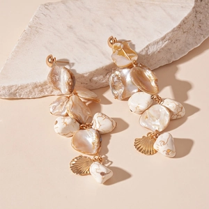 Macro detail of bohemian shell earrings with gold starfishes on a natural stone base