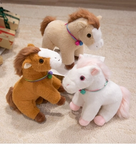 Three plush pony dolls in brown, beige, and white colors with bell collars on a carpet