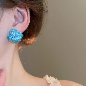 Detailansicht hellblauer quadratischer Cluster-Ohrstecker an einem weiblichen Model
