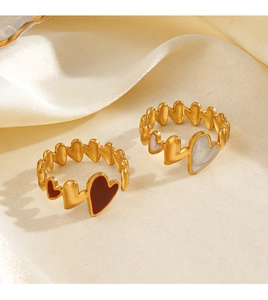 Detail of 18K gold adjustable rings featuring burgundy and marble heart enamel charms