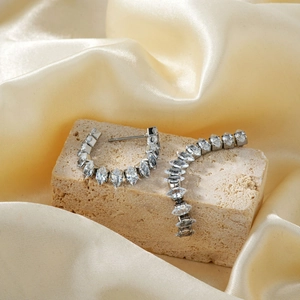 Silver stud earrings with marquise-cut zircons displayed on stone and silk